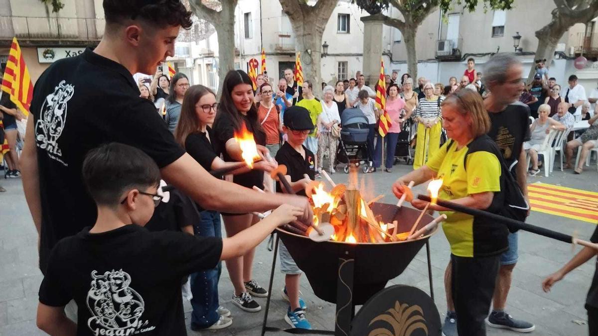 Una cercavila porta la flama des del pont d'entrada a Sant Vicenç fins a l'ajuntament
